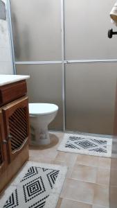 La salle de bains est pourvue de toilettes et d'une douche avec des tapis. dans l'établissement Casarão na Praia de Camboinha a 250 metros do mar, à Cabedelo