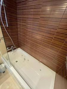 a bathroom with a bath tub with a wooden wall at HOLA ANDORRA - family apartment in Bordes d´Envalira