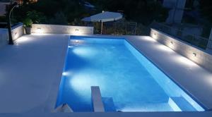 a swimming pool with lights in a backyard at night at Apartments T&M in Vinišće