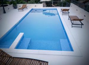 a large swimming pool with benches and chairs in it at Apartments T&M in Vinišće