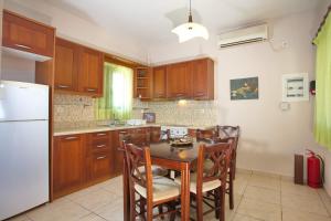 een keuken met een tafel, stoelen en een koelkast bij Villa Κτήμα Νικόλα in Likórrevma +4 foto's