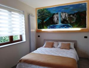 1 dormitorio con 1 cama y una pintura en la pared en Il Sottobosco, en Satriano di Lucania
