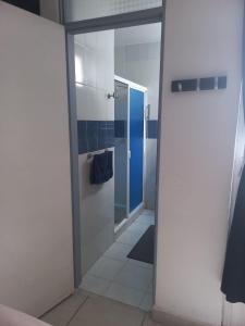 La salle de bains est pourvue de murs bleus et blancs et d'une porte en verre. dans l'établissement Bonito depto con patio y oficina a 7 minutos caminando AICM, à Mexico