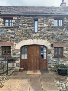 a stone house with a large wooden door at Swallows Barn in Penrith
