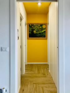 a hallway with a yellow wall and wooden floors at UPLÈ family bike apartment in Lecce