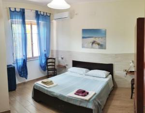 a bedroom with a large bed with blue curtains at Casa Vacanze"Il Bouganville" in Carbonia