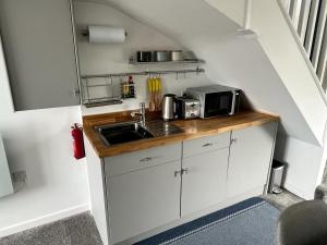 a small kitchen with a sink and a microwave at Godrevy Lighthouse View, Carbis Bay, St Ives, free parking near beach in Carbis Bay