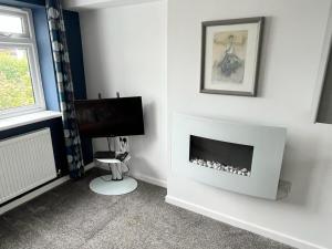 a living room with a fireplace and a television at Godrevy Lighthouse View, Carbis Bay, St Ives, free parking near beach in Carbis Bay