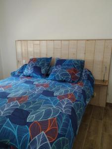 ein Schlafzimmer mit einem Bett mit einer bunten Bettdecke in der Unterkunft La maison en bois in Monteils