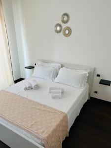 1 cama blanca con 2 toallas y espejo en la pared en Settembre en Sannicandro di Bari