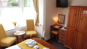 a hotel room with a bed and a desk and chairs at Brackenhurst Guest House in Skegness