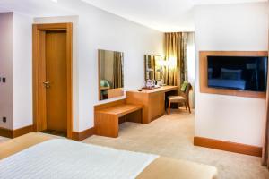 a bedroom with a bed and a desk and a television at SYM Hôtel in Cheraga