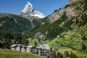 une montagne avec une roue en ferris devant un complexe dans l'établissement Matterhorn FOCUS Design Hotel, à Zermatt