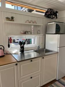 cocina con fregadero y nevera blanca en Dejligt Tinyhouse i Gilleleje, en Gilleleje