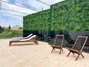 twee stoelen op een patio met een groene muur bij Nice Nordic Style Villa 8 min from the beach. in El Campello