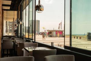 ein Restaurant mit Blick auf den Strand aus einem Fenster in der Unterkunft Palace Hotel Zandvoort in Zandvoort + 168 Fotos