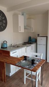 弗雷埃勒的住宿－L'Eden，厨房配有木桌和白色橱柜。