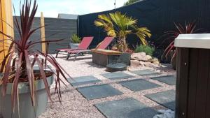 弗雷埃勒的住宿－L'Eden，后院的庭院配有粉红色的椅子和植物