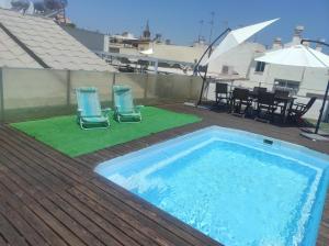 a swimming pool on a deck with two chairs and a table at Habitación y baño en planta independiente en centro de sevilla in Seville