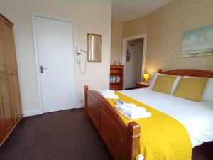 a bedroom with a large bed with a yellow blanket at Brackenhurst Guest House in Skegness