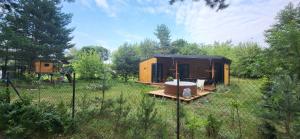 a tiny house in a field with a fence at Stacja Roztocze in Majdan Kasztelański