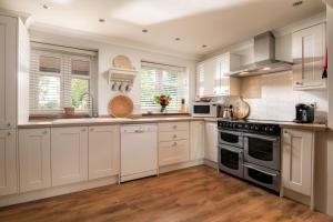 a kitchen with white cabinets and a stove top oven at End Cottage in Fakenham