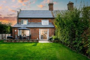 a brick house with a patio and a lawn at End Cottage in Fakenham