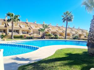 a swimming pool in front of a building with palm trees at Casa en Punta Prima in Alicante