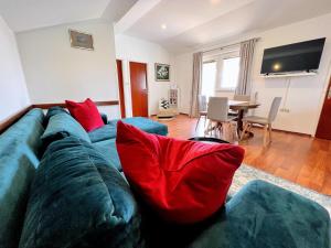 uma sala de estar com um sofá azul e almofadas vermelhas em Apartments Muntidor em Rab