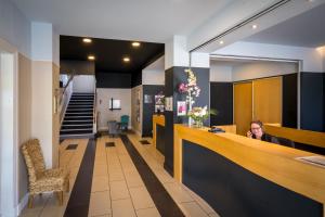 a woman sitting at a counter in a lobby at Best Western Adagio Saumur in Saumur