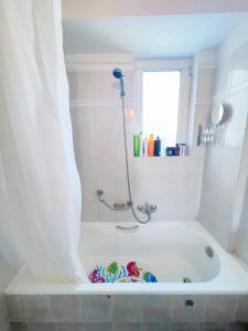 a white bath tub with a shower in a bathroom at 花园露台 温馨舒适的高层全景公寓 免费公共停车位 距机场15分钟 设有儿童主题亲子房 in Athens