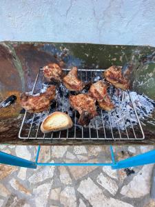 a grill with meat and a bread on it at Vintage Mediterranean house in Himare