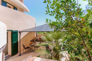 patio z krzesłami i stołem z niebieskim parasolem w obiekcie B&B Villa Zola w mieście Capoterra