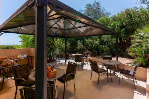 patio ze stołami i krzesłami pod baldachimem w obiekcie B&B Villa Zola w mieście Capoterra
