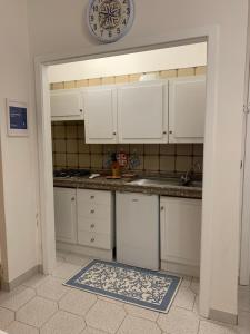 a kitchen with white cabinets and a clock on the wall at APPARTAMENTO LIDO 2 in Alghero