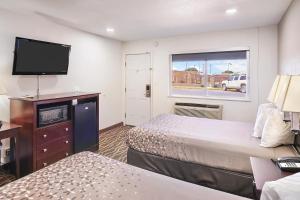 a hotel room with two beds and a flat screen tv at Carlsbad Inn , New Mexico in Carlsbad