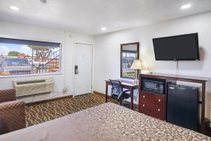 Habitación de hotel con cama, escritorio y TV. en Carlsbad Inn , New Mexico, en Carlsbad