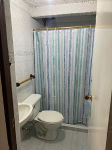 a bathroom with a toilet and a shower curtain at CASA FAMILIAR AMPLIA MUY FRESCA in Medellín