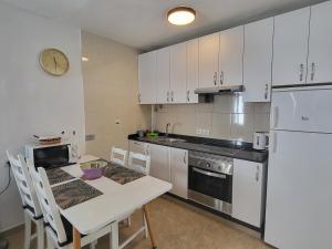 プエルト・デル・カルメンにあるGueldera Apartmentsのキッチン(白いテーブル、白い冷蔵庫付)
