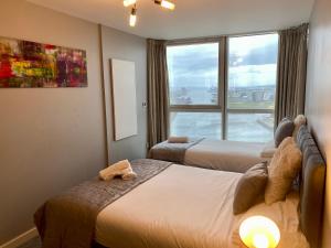 a hotel room with two beds and a window at Titanic and Sea View Belfast 2 bedroom Apartment City Centre in Belfast