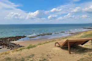 a bench sitting on the side of a beach at Magnifique Studio 2 personnes - VUE MER "La Perle de Jade" in Saint-Michel-Chef-Chef