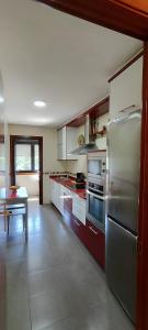 eine Küche mit einem Kühlschrank aus Edelstahl und einem Tisch in der Unterkunft Barosa rooms in Barro