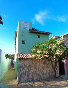 a building with a tree in front of a fence at Suítes Preguiça in Canoa Quebrada