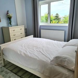 a bedroom with a white bed and a window at Benllech Beach in Benllech