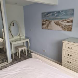 a bedroom with a bed and a dresser and a mirror at Benllech Beach in Benllech