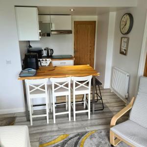 uma cozinha com uma mesa de madeira e algumas cadeiras em Benllech Beach em Benllech