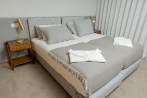 - une chambre dotée d'un grand lit avec des draps et des oreillers blancs dans l'établissement QUINTA ALTO DO RIO, à Cinfães