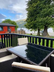 a table and chairs on a balcony with a tree at Cozy Cabin with Stunning Loch Lomond Views in Rowardennan