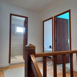 einen Flur mit zwei Spiegeln und einer Holztreppe in der Unterkunft Maison de village entre estuaire et océan in Saint-Yzans-de-Médoc