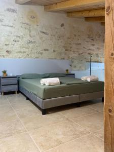 een slaapkamer met een bed en een stenen muur bij Casa di Fragkiskos. Ένα σπίτι μέσα στη φύση. in Kondomárion